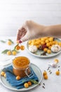 Woman hand holds yellow cherry plum over glass jar of homemade DIY natural canned yellow cherry plum sauce chutney with chilli or Royalty Free Stock Photo