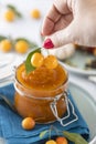 Woman hand holds yellow cherry plum over glass jar of homemade DIY natural canned yellow cherry plum sauce chutney with chilli or Royalty Free Stock Photo