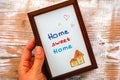 Woman hand with Home sweet home picture in wooden frame. Wood background Royalty Free Stock Photo