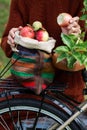 Woman hand keeps knitted colorful bag with apples on bike