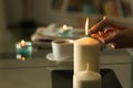 Woman hand lighting candles with lighter at night