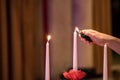 Woman hand lightning candles on Banquet with red table setting