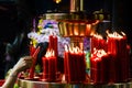 Woman hand lights red candles in Buddhist temple, Taiwan, China. Religious concept, spirituality, faith, God. Buddha, symbol, Asia