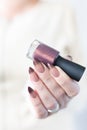 Woman hand with manicure and pink bottle with nail polish