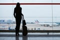 Woman with hand luggage in international airport, looking through the window at planes Royalty Free Stock Photo