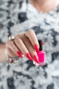 Woman hand with manicure and pink bottle with nail polish