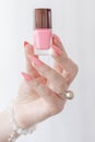 Woman hand with manicure and pink bottle with nail polish