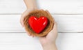 Woman Hand and Men Hand Hold Red Heart in bird nest on white wood background. Couple Protect Love or Health Concept with Copy Royalty Free Stock Photo