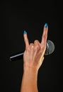 Woman hand with microphone and devil horns isolated on black Royalty Free Stock Photo