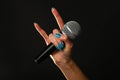 Woman hand with microphone and devil horns isolated on black Royalty Free Stock Photo