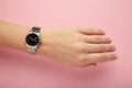 Woman hand with modern watch showing 10:10 o'clock on pink background
