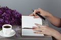Woman hand notepad and coffee with lilac on table