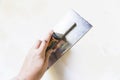 Woman hand with old metal spatula to equalize plaster filler on the wall Royalty Free Stock Photo