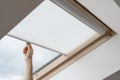 Woman hand open blinds on attic or mansard window