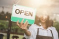 Woman hand open sign board on the door cafe or restaurant hang on door at entrance