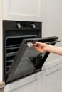 Woman hand opening black built-in oven in white kitchen cabinet Royalty Free Stock Photo