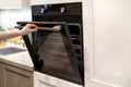 Woman hand opening built-in oven in white kitchen cabinet Royalty Free Stock Photo