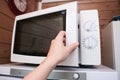 Woman hand opening microwave oven in order to prepare, heat food for lunch or dinner, kitchen elecrtric appliances using