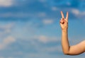 Woman hand over clouds blurred background doing the victory gesture Royalty Free Stock Photo