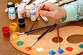 Woman hand with paintbrush, palette, cans and tubes of paint