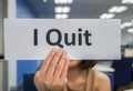 Woman hand with paper sheet of I quit in workplace