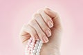 Beautiful french manicure nail studio. Natural nail art design. Woman hand with a pearl necklace. Royalty Free Stock Photo