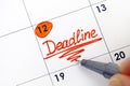 Woman hand with pen writing reminder Deadline in calendar