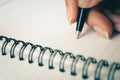 Woman hand with pen writing on white notebook.