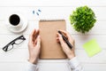 Woman hand with pencil writing on notebook and hold coffee cup. Woman working on office table with coffee Royalty Free Stock Photo