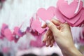 Woman Hand pick pink heart shape Lucky Draw attached to white ribbon on wishing tree in charity event. Games, that prizes are