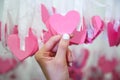 Woman Hand pick pink heart shape Lucky Draw attached to white ribbon on wishing tree in charity event. Games, that prizes are