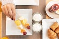 Woman hand picking fresh fruits. Delicious Breakfast top view fresh croissant, fruits and yogurt. Still life of sweets