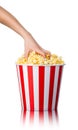 Woman hand picking popcorn from striped bucket isolated on white background Royalty Free Stock Photo