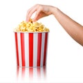 Woman hand picking popcorn from striped bucket isolated on white background Royalty Free Stock Photo