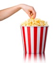 Woman hand picking popcorn from striped bucket isolated on white background Royalty Free Stock Photo