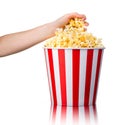 Woman hand picking popcorn from striped bucket isolated on white background Royalty Free Stock Photo