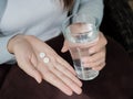 Woman hand with pills medicine tablets and glass of water Royalty Free Stock Photo