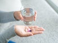 Woman hand with pills medicine tablets and glass of water in her Royalty Free Stock Photo