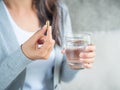 Woman hand with pills medicine tablets and glass of water in her Royalty Free Stock Photo