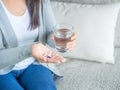 Woman hand with pills medicine tablets and glass of water in her Royalty Free Stock Photo