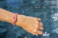 Woman hand with pink bracelet. Women& x27;s jewelry. Beautiful rose tones bracelet. Swimming pool water as background