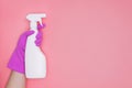 Woman hand in pink rubber protective glove holding cleaning agent bottle on pink background. Royalty Free Stock Photo