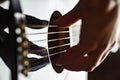 Woman hand plays strings on guitar black, strings stretched, close-up selective focus