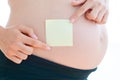 Woman hand posting empty adhesive notes on her pregnant belly Royalty Free Stock Photo