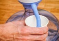 Woman hand pouring water in paper cup from bottle with water pump Royalty Free Stock Photo