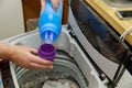 Woman hand pours liquid powder into the drum of the washing machine laundry Royalty Free Stock Photo