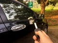 Woman hand press remote control of car key at parking to lock or unlock the car. Royalty Free Stock Photo