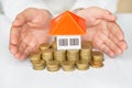 Woman hand protecting on stack coins and house model on table, Saving money for house and real estate Royalty Free Stock Photo