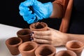 Woman hand with protective gloves holding the terracotta pot and pouring soil in the flower pot Royalty Free Stock Photo