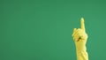 Woman hand with protective rubber glove shaking hand, waving finger in denial over green chroma key background. Sign of